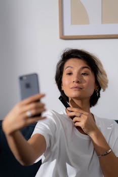 A woman takes a selfie while showcasing a beauty product, capturing a modern lifestyle moment.