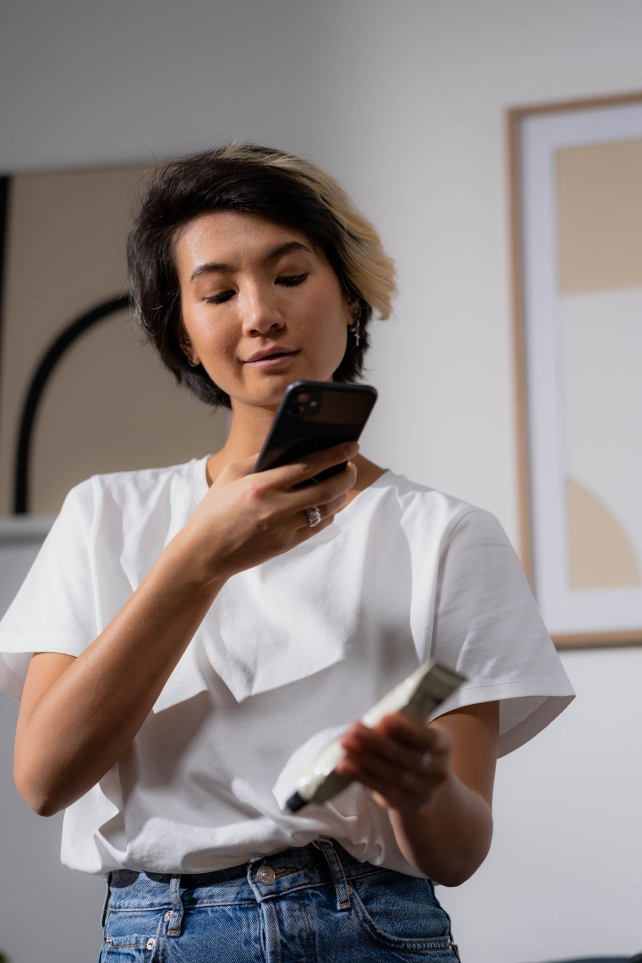 Young skincare brand founder scanning a product with her smartphone camera indoors