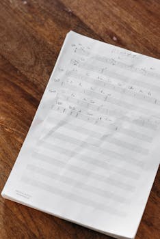 A detailed shot of a handwritten music sheet placed on a wooden table, showcasing musical notes and composition.