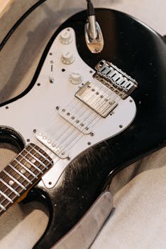 Detailed photo of a black electric guitar with focus on strings and knobs, showcasing its design.