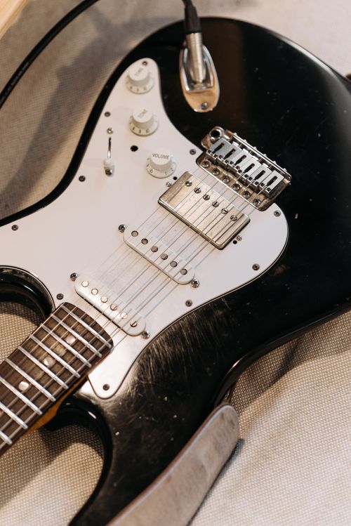 Free Detailed photo of a black electric guitar with focus on strings and knobs, showcasing its design. Stock Photo