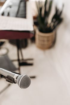 Close-up of a microphone in a music studio with a blurred background, featuring keyboard.