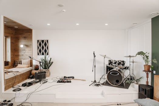 A modern music studio featuring a drum set, guitar, and cozy seating area for musicians.