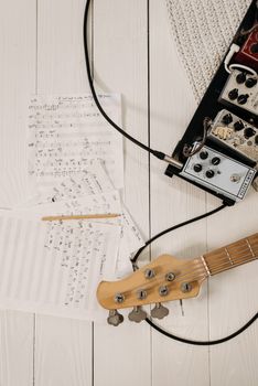 Overhead shot of a guitar, pedals, and music sheets on a wooden floor, perfect for music enthusiasts.