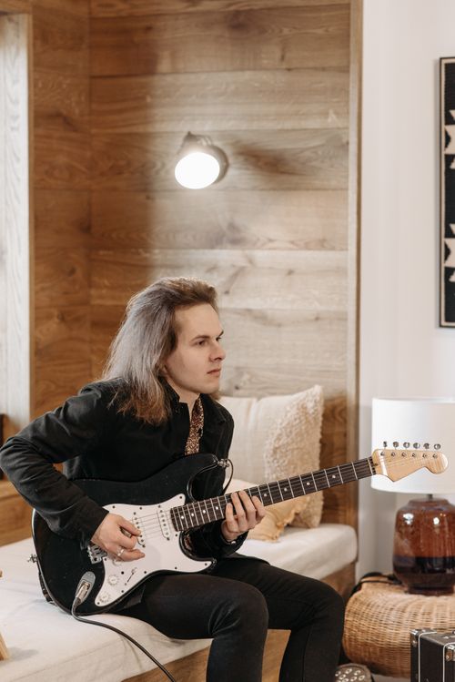 Free Portrait of a man playing an electric guitar in a cozy indoor setting. Stock Photo