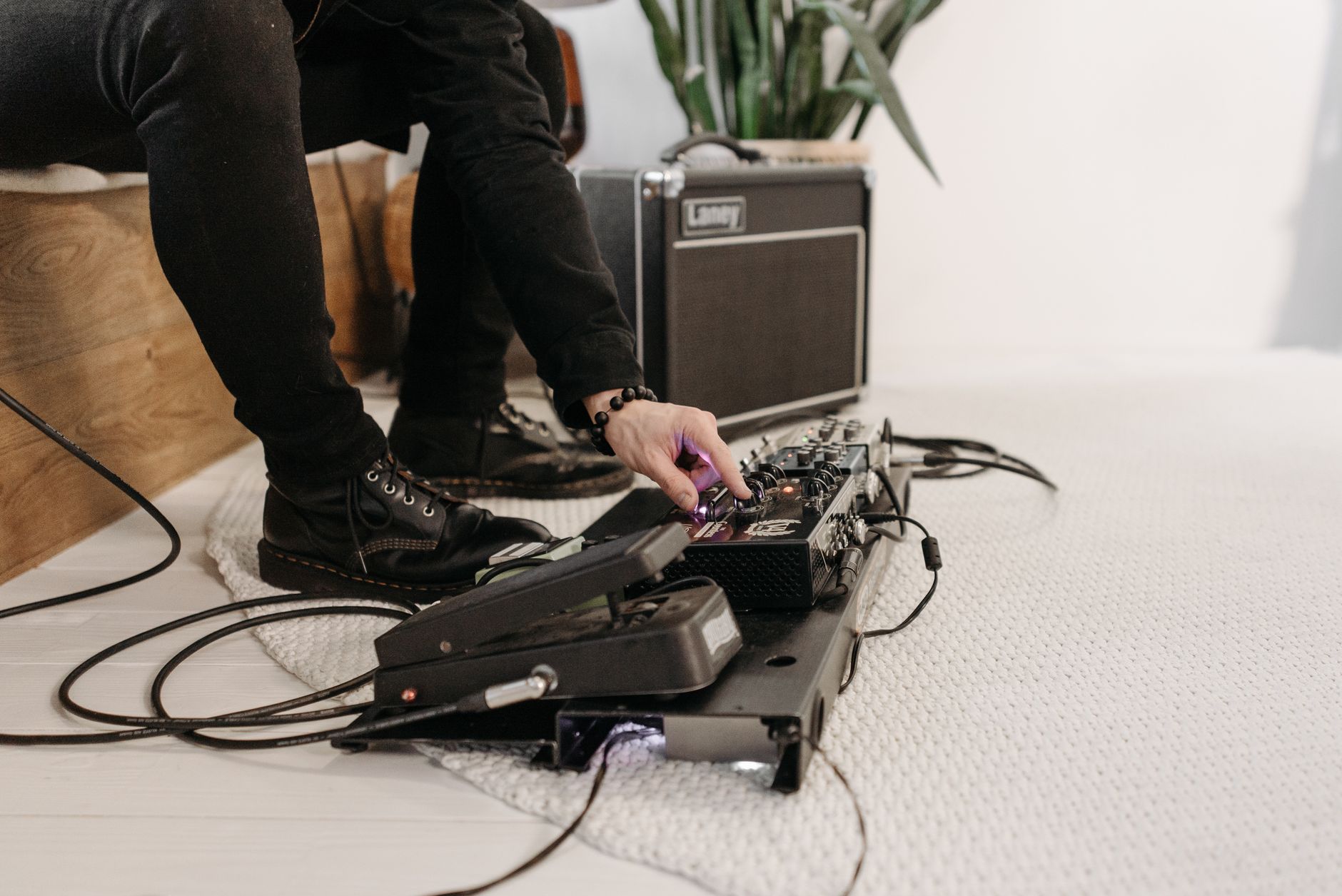 Musician setting up pedal board in a cozy indoor environment, enhancing sound.