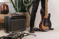 Person in Black Denim Jeans and Black Leather Boots Standing Beside Black Guitar Amplifier