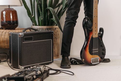 Free Close-up of a musician with an electric bass guitar and amplifier in a stylish indoor setting. Stock Photo