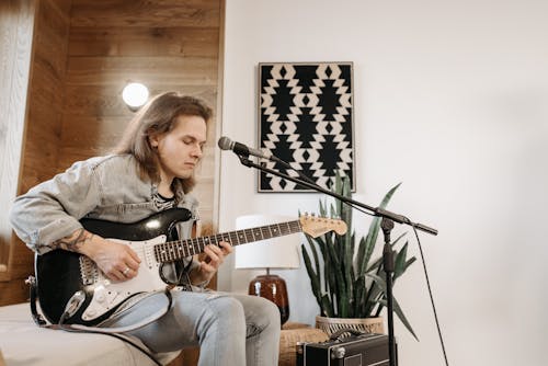 A Man Playing the Guitar while Sitting Indoors