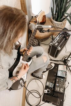 A musician playing an electric guitar surrounded by musical equipment indoors.