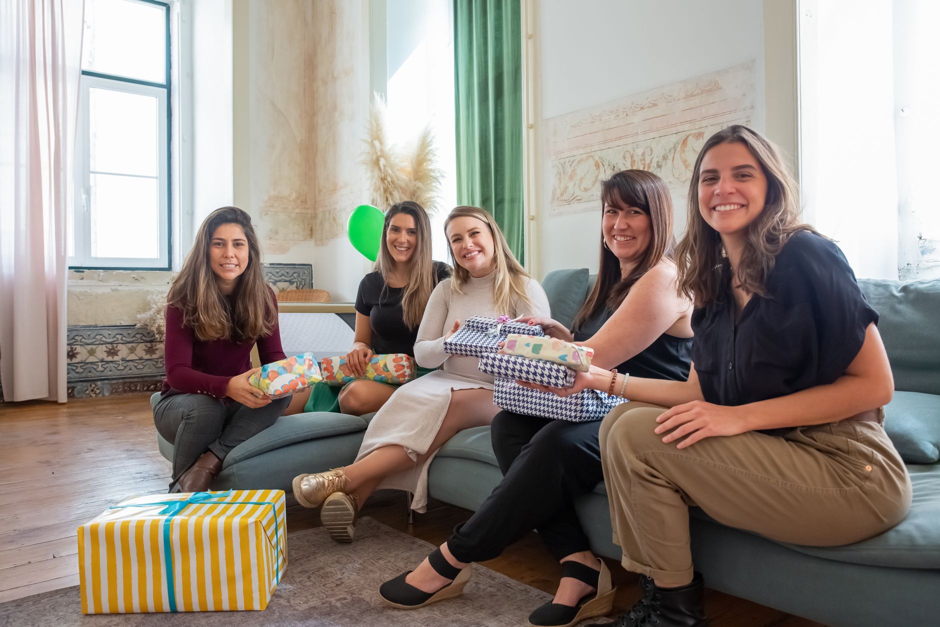A joyful indoor baby shower celebration with women sharing gifts and smiles.