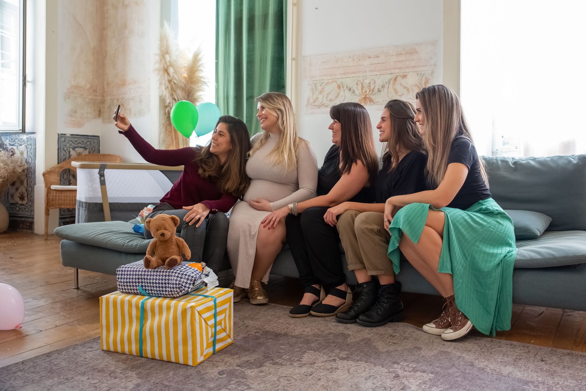 Group of women celebrating a baby shower with gifts and smiles, capturing memories indoors.