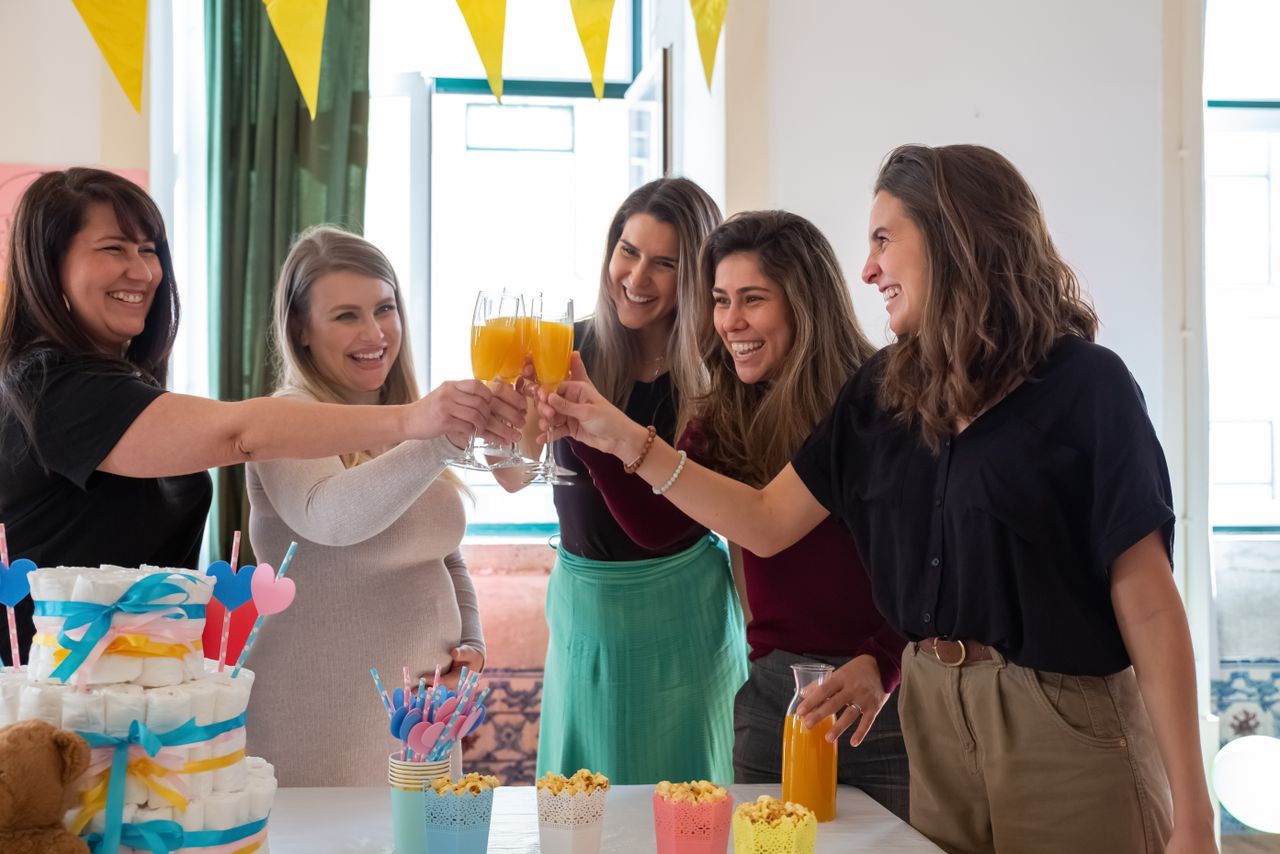 group of women celebrating a baby shower with orange juice toasts and