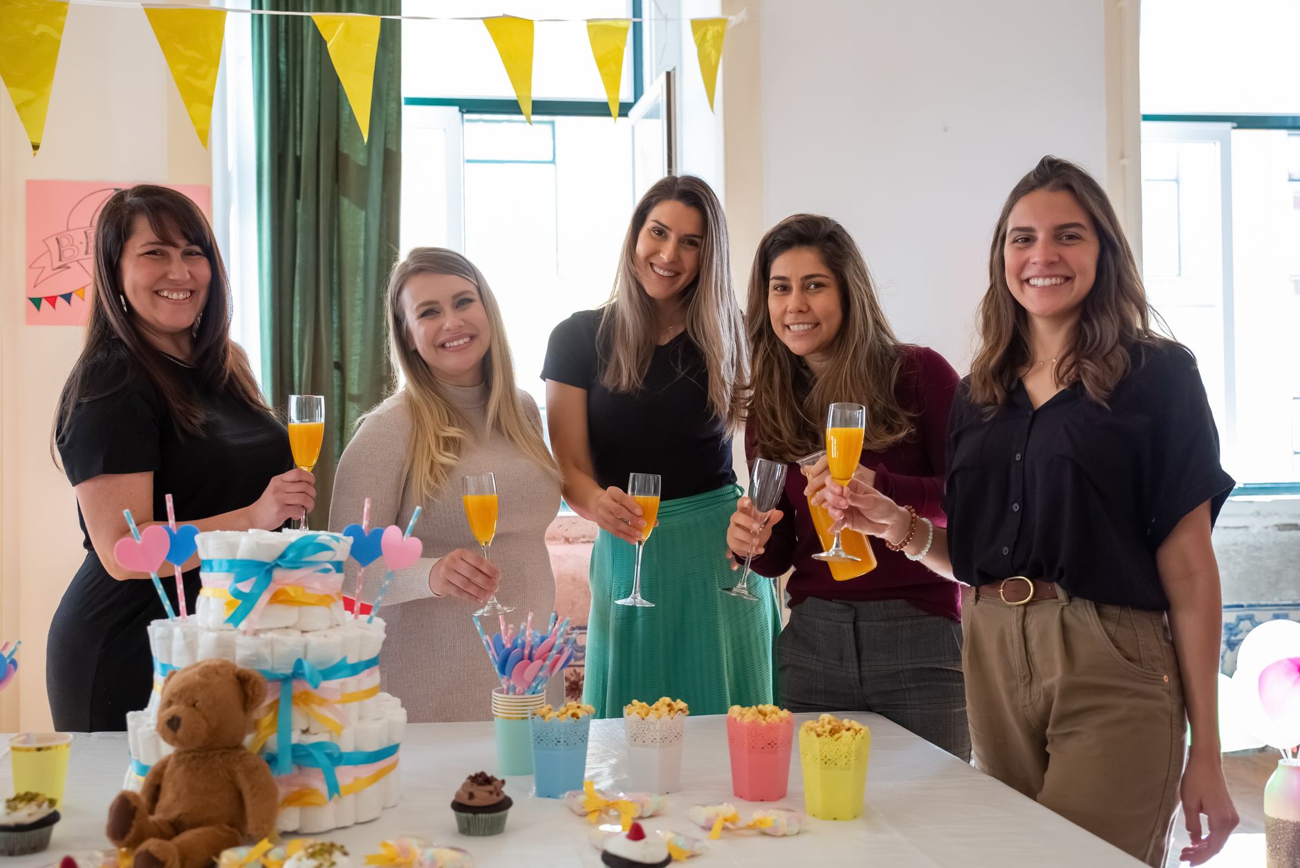 Women celebrate a baby shower with drinks and decor, creating festive memories.