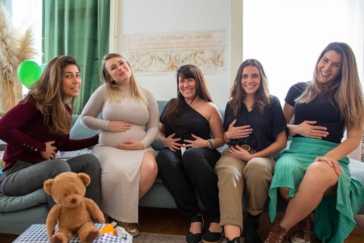 Women Sitting On The Couch Touching Their Tummy