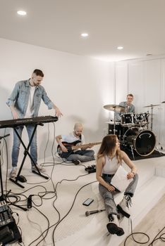 A lively group of young musicians rehearsing in a modern indoor studio setting.