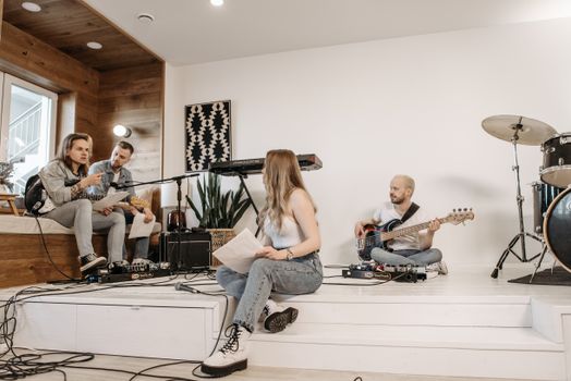 A group of young musicians rehearsing with instruments in a modern studio setting.