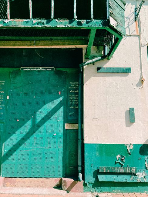 Details of exterior of old industrial building with metal shuttered door and shabby walls on sunny day in suburban district
