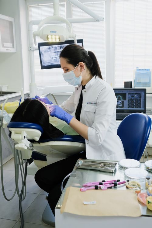 Free A female dentist cleaning a patient's teeth in a modern dental clinic. Stock Photo