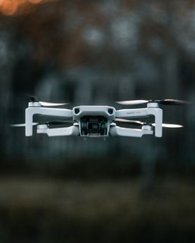 Modern quadcopter with camera for remote control and shooting from height flying above ground