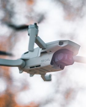 Low angle of modern unmanned aerial drone with propellers flying in air and shooting video