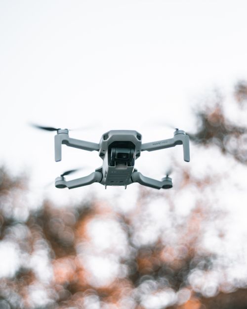 Free Low angle of professional unmanned drone flying over countryside against blurred trees at daytime Stock Photo