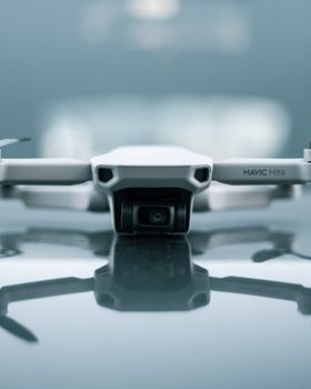 Modern drone unmanned aerial vehicle for aerial photography policing and surveillance placed on reflecting surface