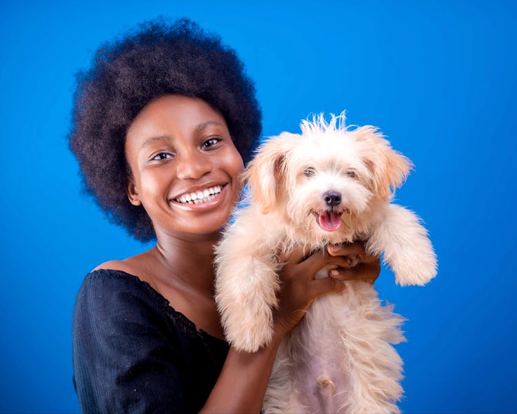 Portrait Of Smiling Woman With Dog On Blue Background