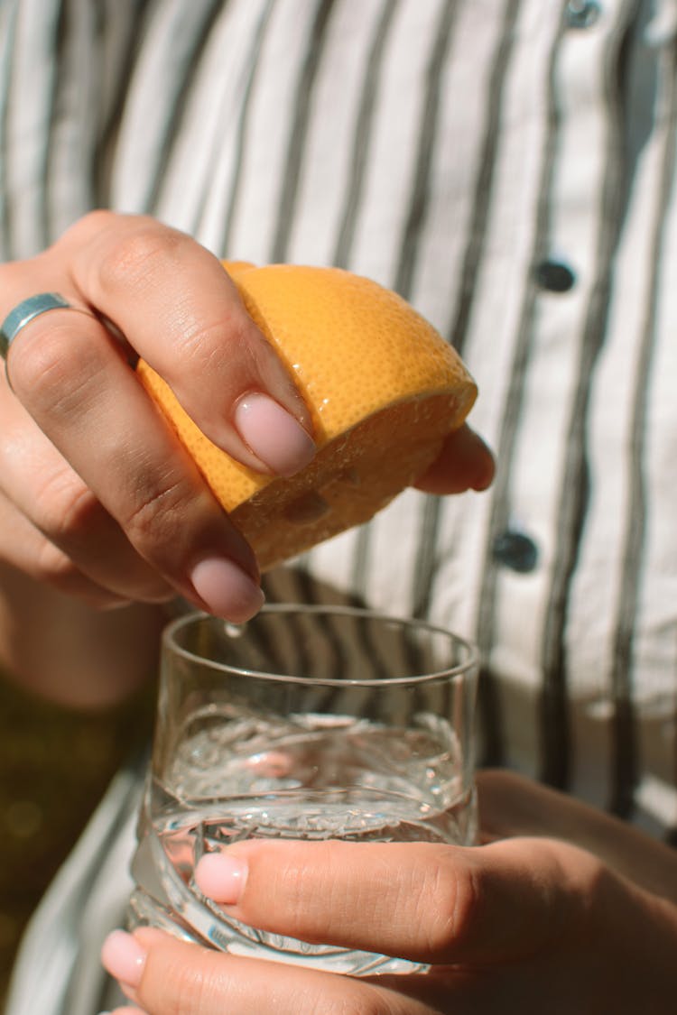 Unrecognizable Woman Squeezing Lemon Juice Into Water