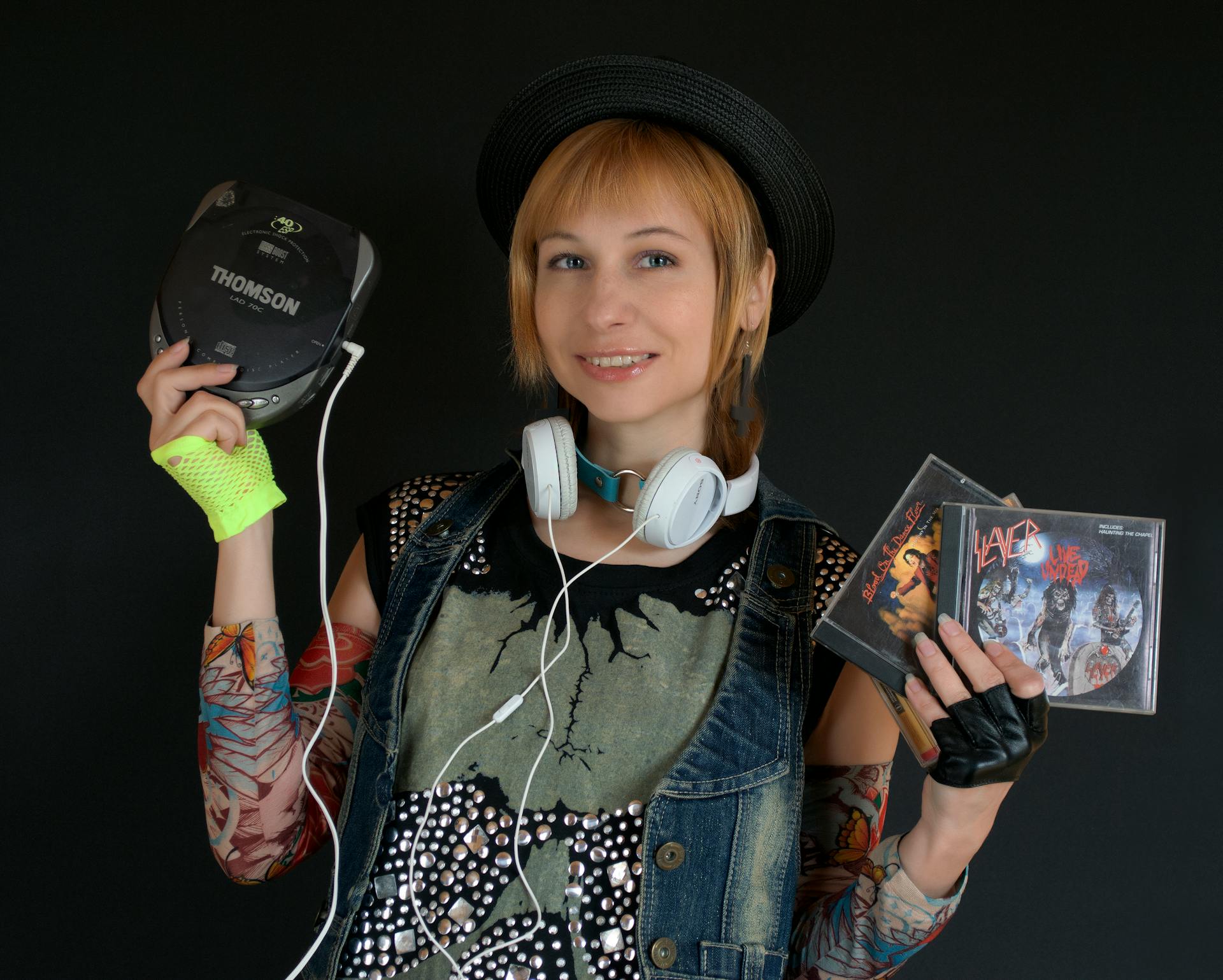 A stylish woman with a retro look poses with CDs and a portable CD player, celebrating 90s music culture.