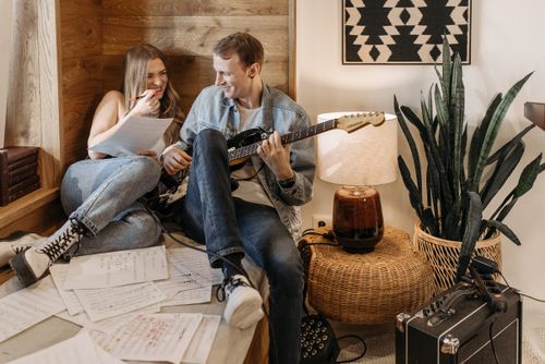 Free A couple practicing music together with an electric guitar in a cozy room setting. Stock Photo