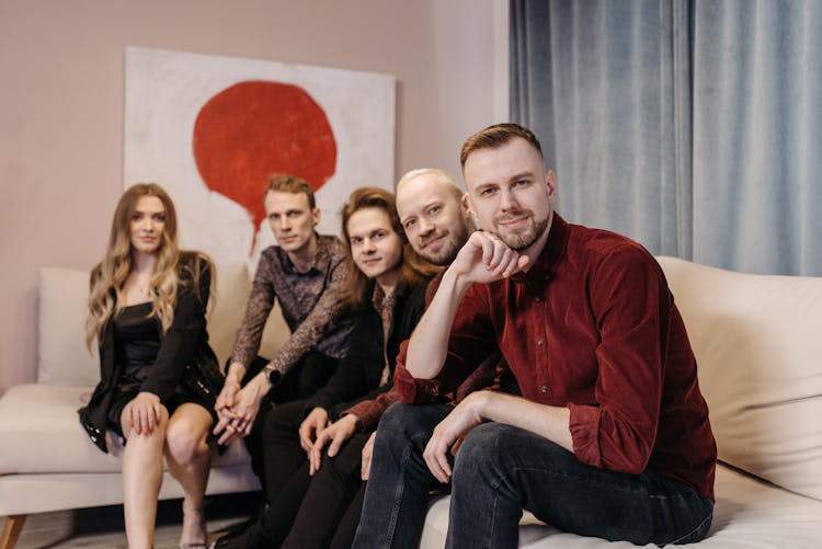 People Sitting On A Couch While Smiling At The Camera