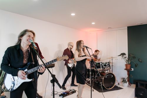 Free Indie band performing live indoors with electric guitar, drums, and vocals. Energetic and vibrant atmosphere. Stock Photo