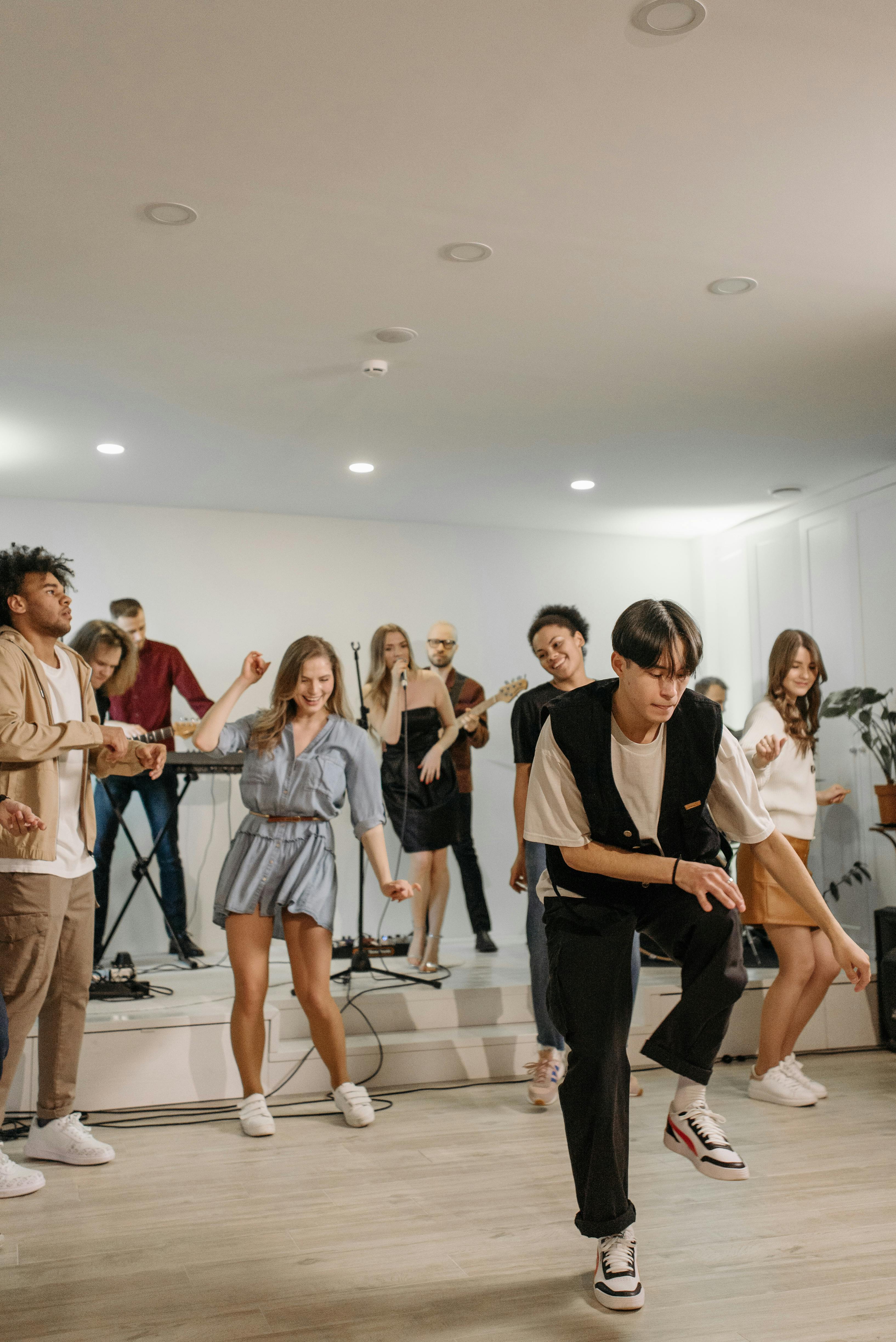 Energetic group of friends dancing at an indoor concert with a live band.