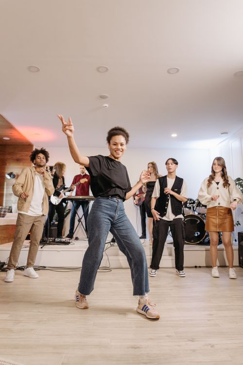 Free Friends enjoying a live band performance indoors, dancing with joy and energy. Stock Photo