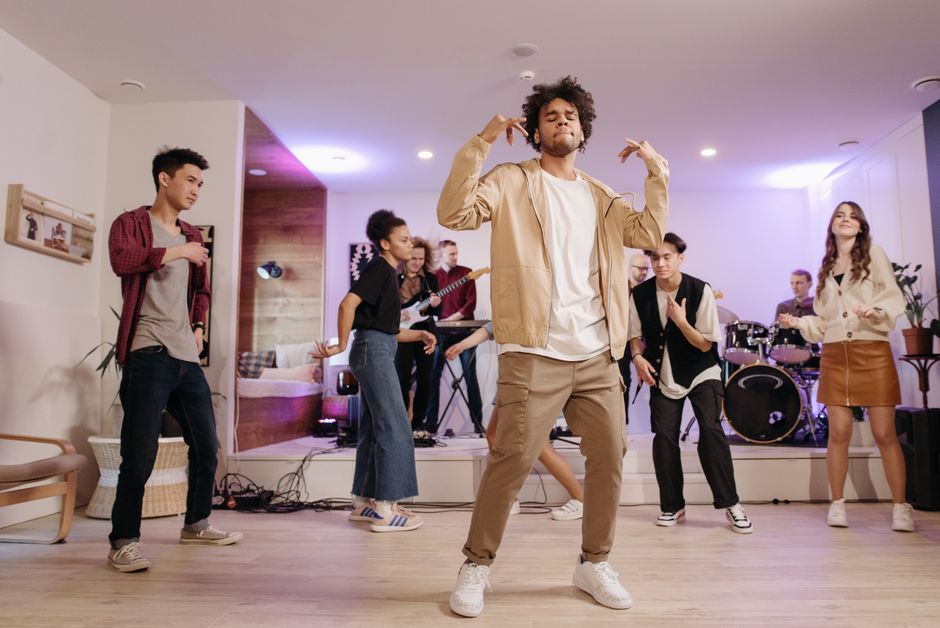 Group of young adults dancing and enjoying live music in a cozy home setting.
