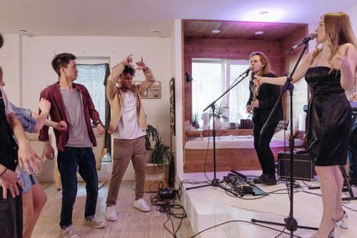 Free An energetic home concert with a live band and dancing audience members enjoying music. Stock Photo
