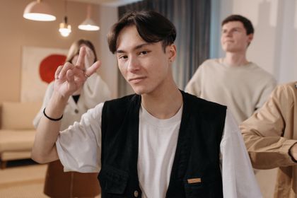 Young man making a peace sign, posing confidently in an indoor setting — photo by Pavel Danilyuk on Pexels