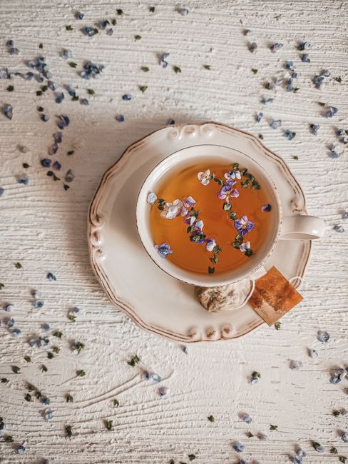 Top view of a floral tea cup on a decorative saucer with scattered flowers.