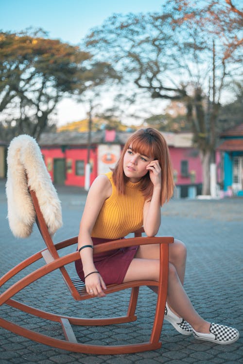 Woman in Yellow Tank Top Sitting on a Rocking Chair