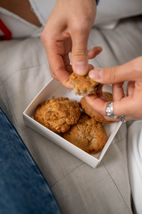 Free A person holding freshly baked cookies in a white box, emphasizing warmth and comfort. Stock Photo