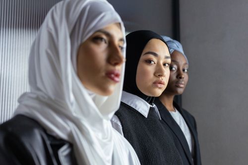 Free Three diverse women wearing hijabs pose confidently indoors, representing multicultural beauty and strength. Stock Photo
