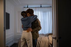 A heartfelt embrace between a loving couple in a sunlit bedroom, conveying warmth and affection.