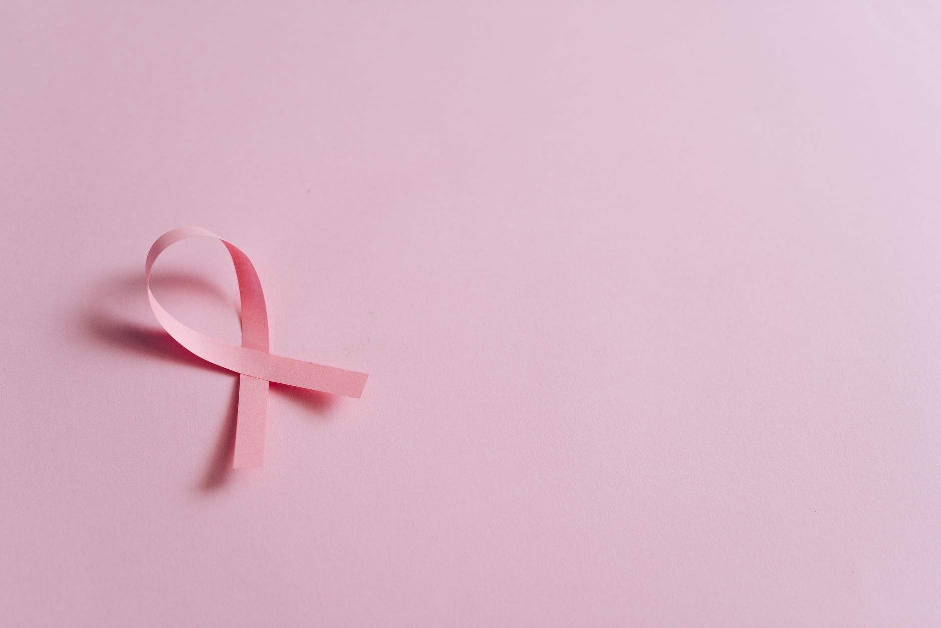 natural cancer support protocols for breast cancer — Minimalist pink ribbon symbolizing breast cancer awareness on a pink background.