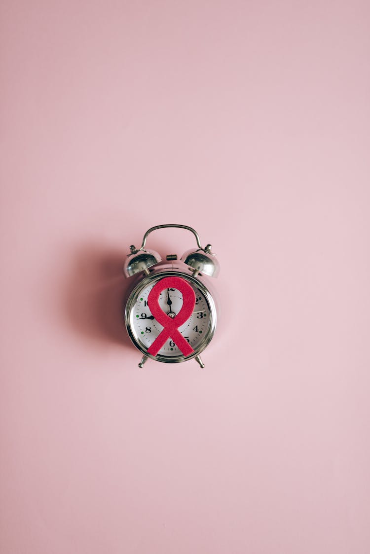 A Pink Ribbon Paper Cut Out On An Alarm Clock