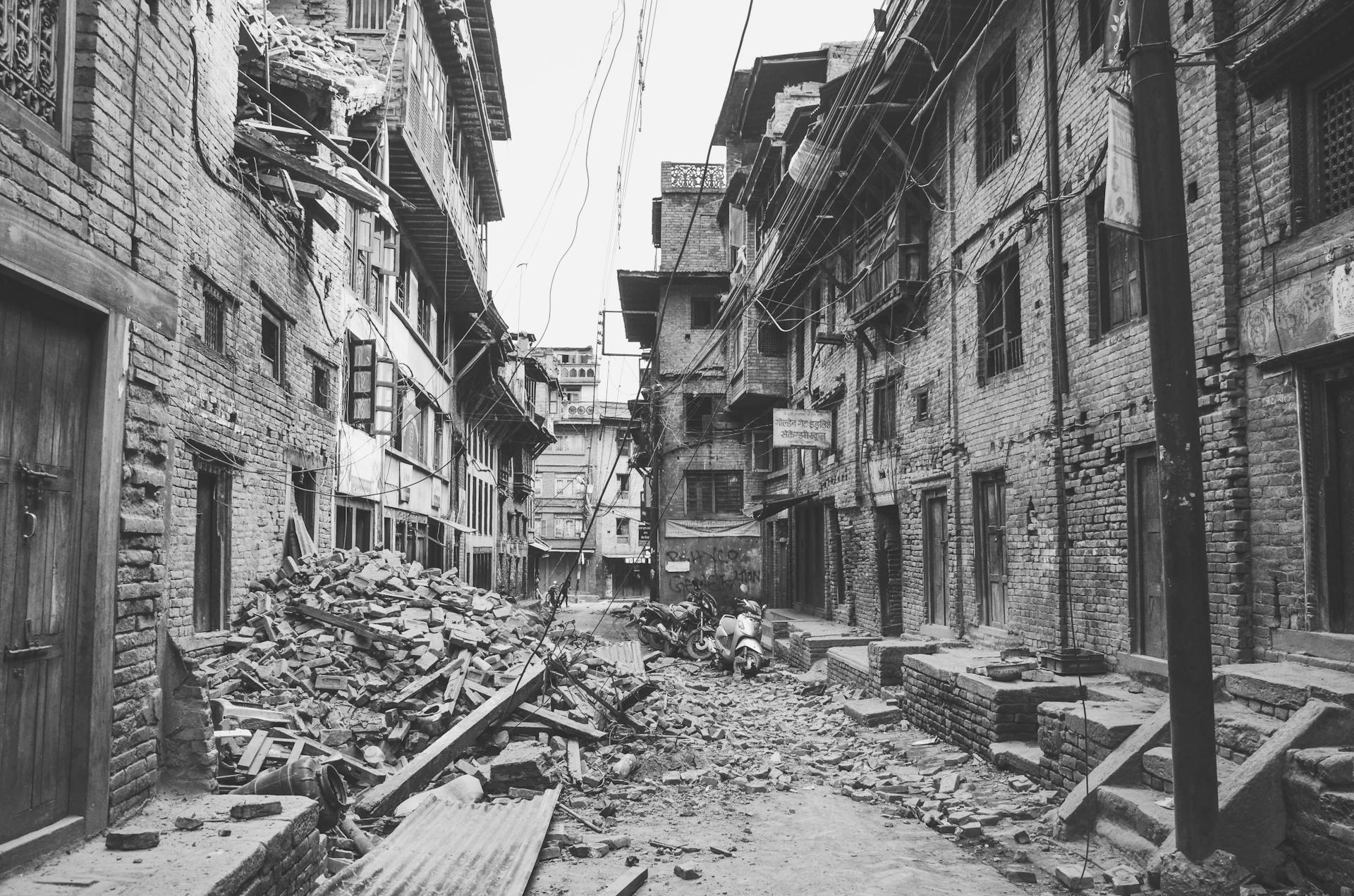 A dramatic view of earthquake destruction in Bhaktapur, Nepal, showing damaged buildings and rubble-filled streets.