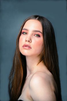 Beautiful woman with long hair posing against a blue background, showcasing elegance and poise.