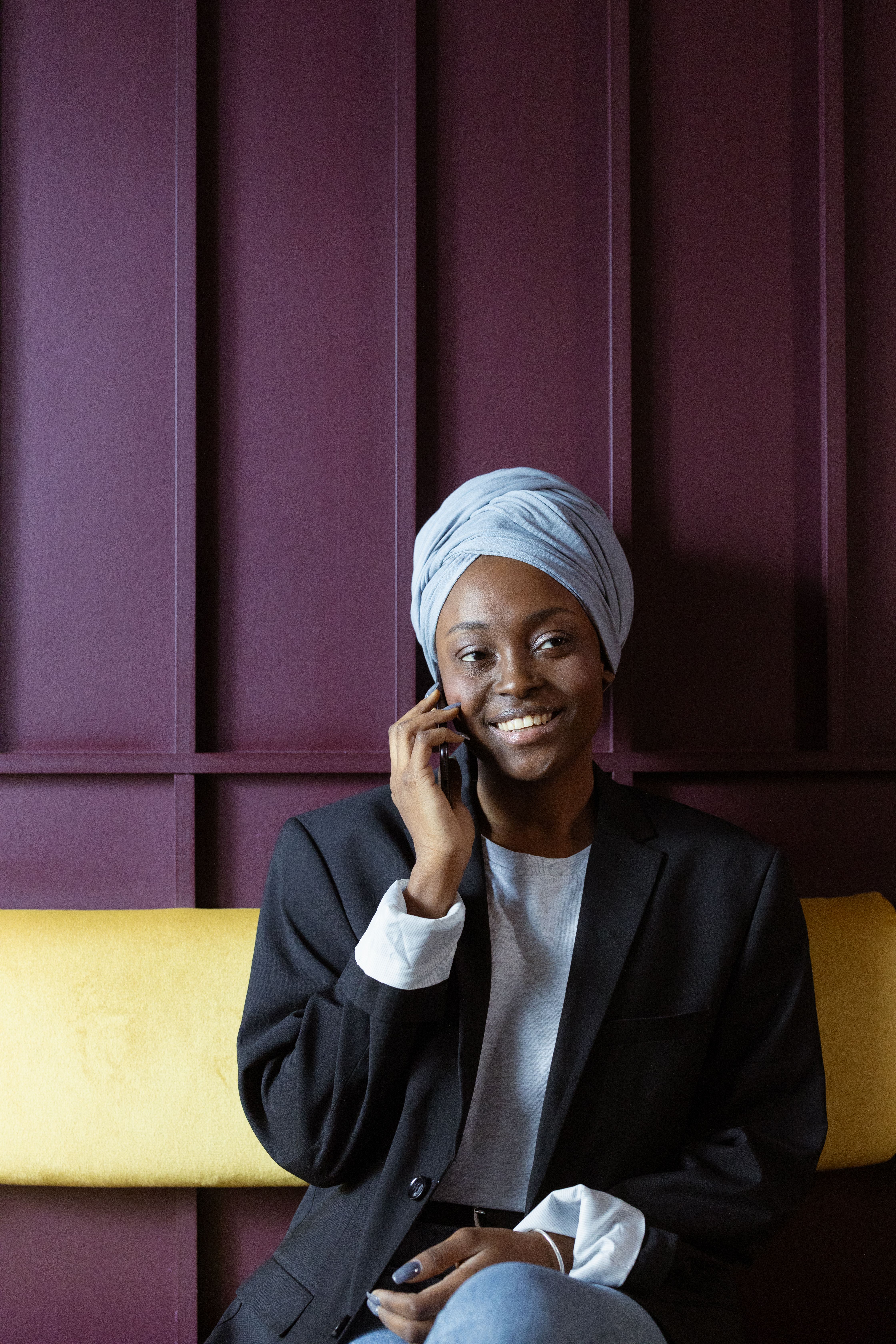 Black Muslim lady in hijab talking on phone on couch · Free Stock Photo