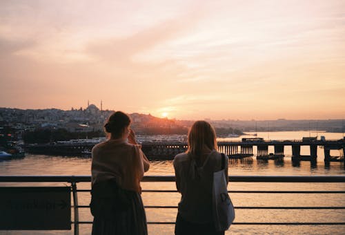 Back View Shot of Women Standing by the Metal Railings