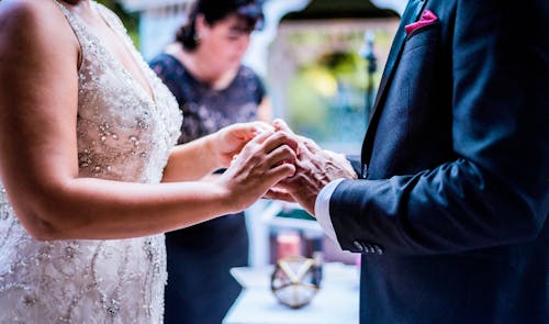 Crop newlywed couple putting on rings during wedding ceremony